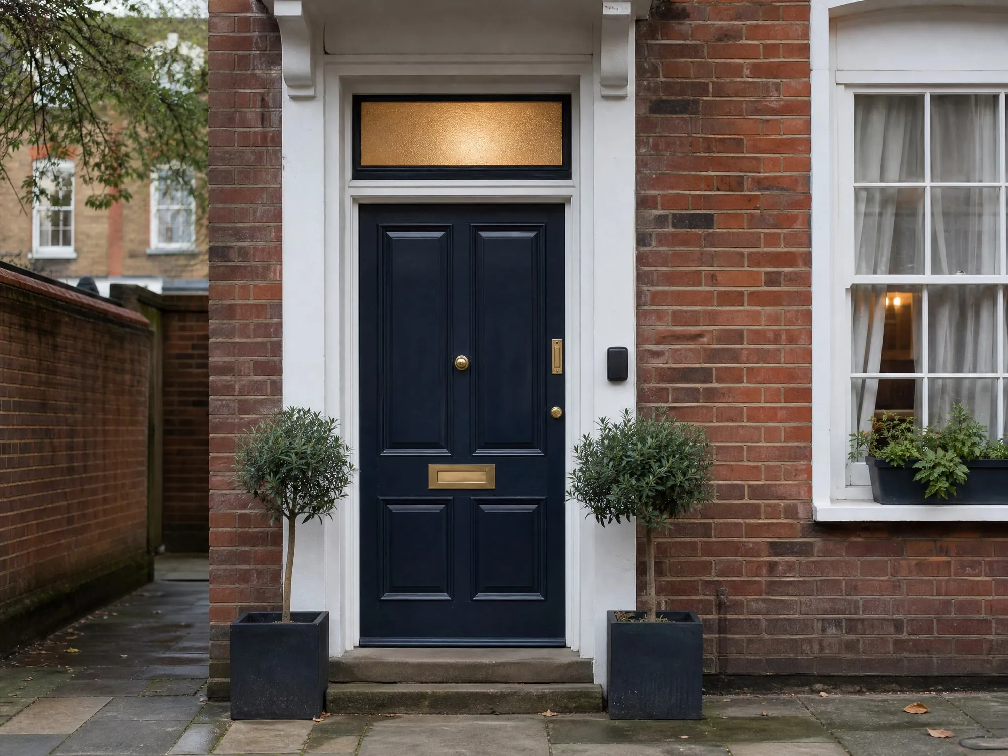 A navy front door with brass fittings on a red-brick townhouse