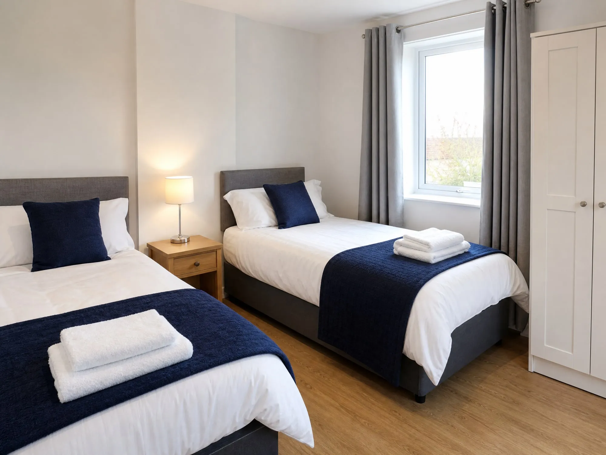 A twin bedroom with two single beds, navy throws and fresh towels